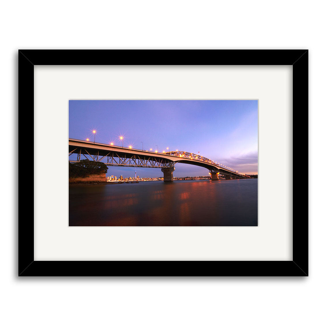 The Auckland Harbour Bridge - RP090 features a framed dusk photograph of the illuminated bridge over New Zealand waters with distant city lights, printed on archival quality matte paper for stunning, long-lasting photographic prints.