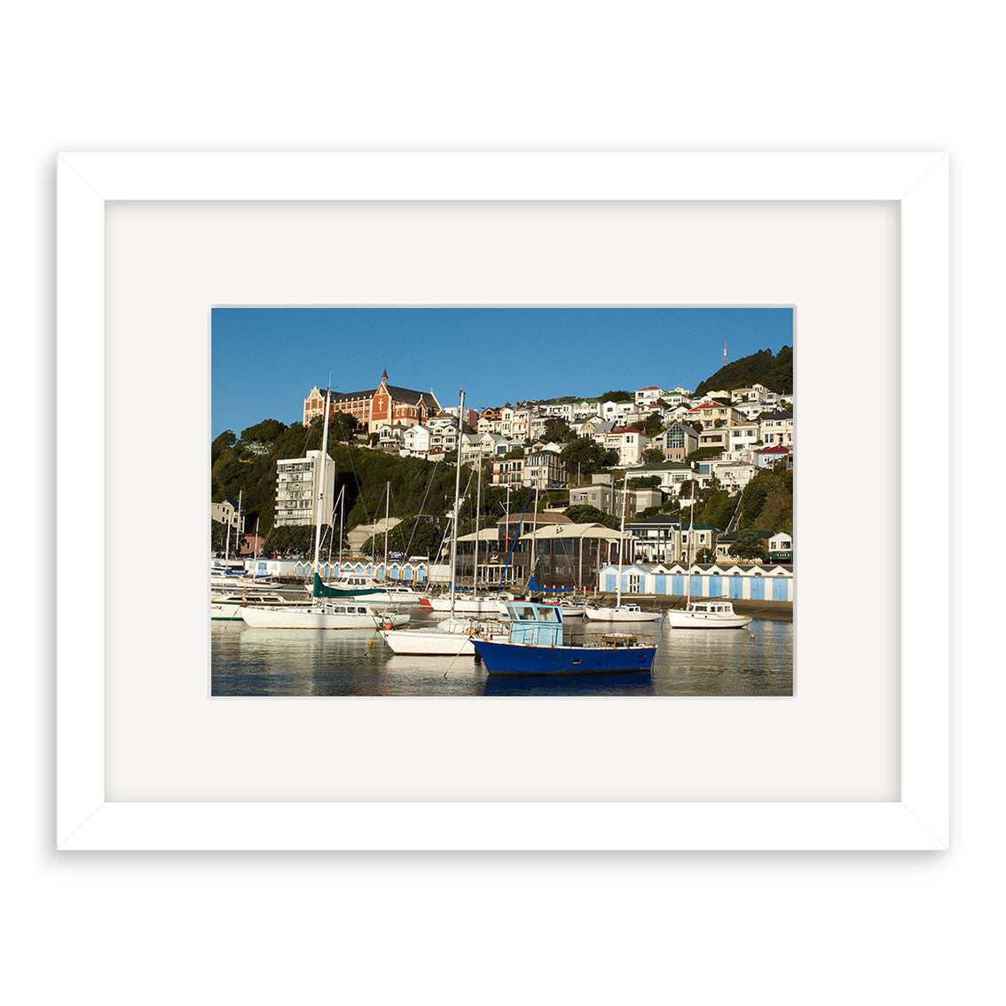 Oriental Bay Boats - RP104: A framed photographic print of a coastal New Zealand town with hillside homes and moored boats, printed on archival quality paper for lasting beauty.