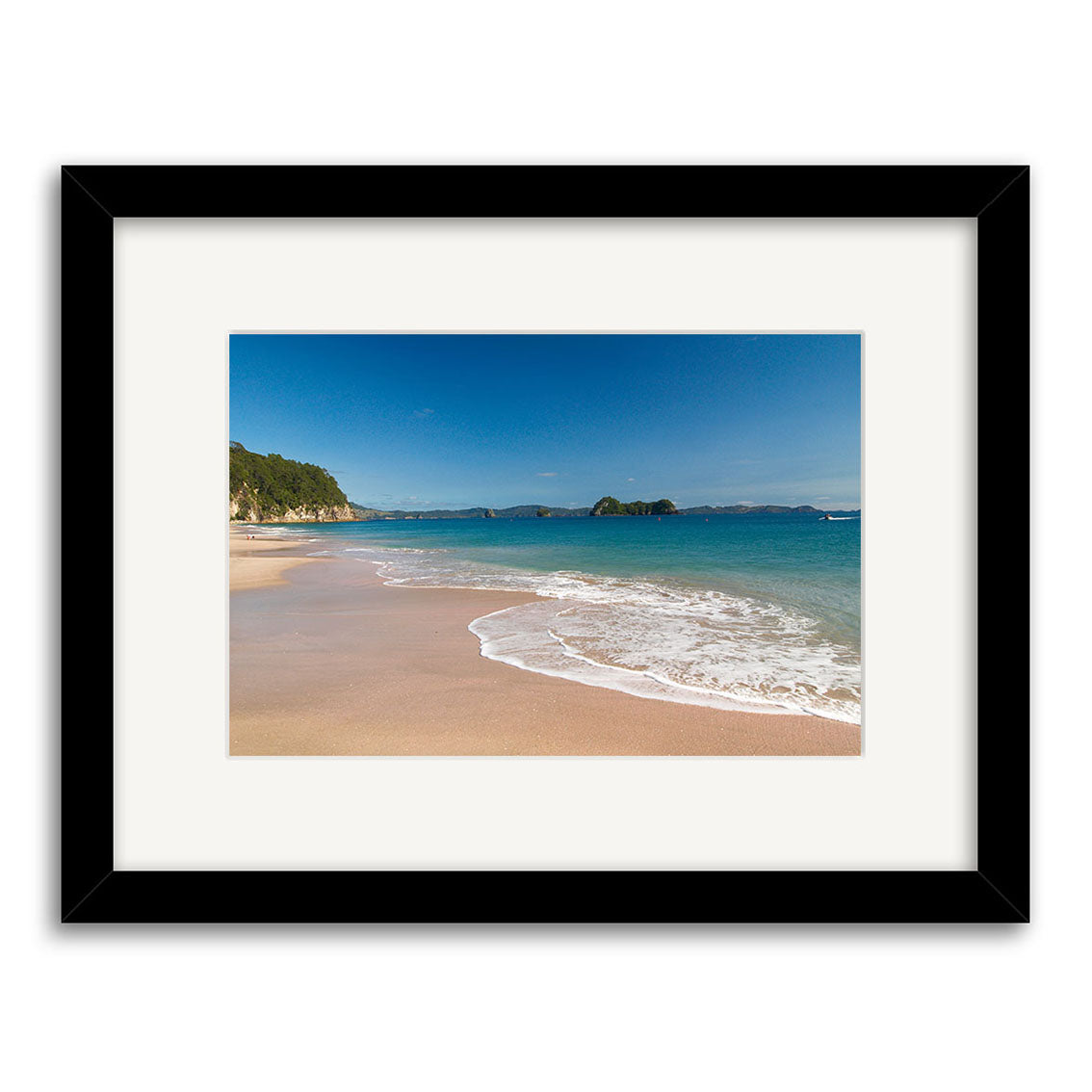 The Hahei Beach - RP126 framed photo captures a sandy New Zealand shore with gentle waves, clear blue water, distant islands, and greenery. Printed on archival quality matte paper for lasting beauty.