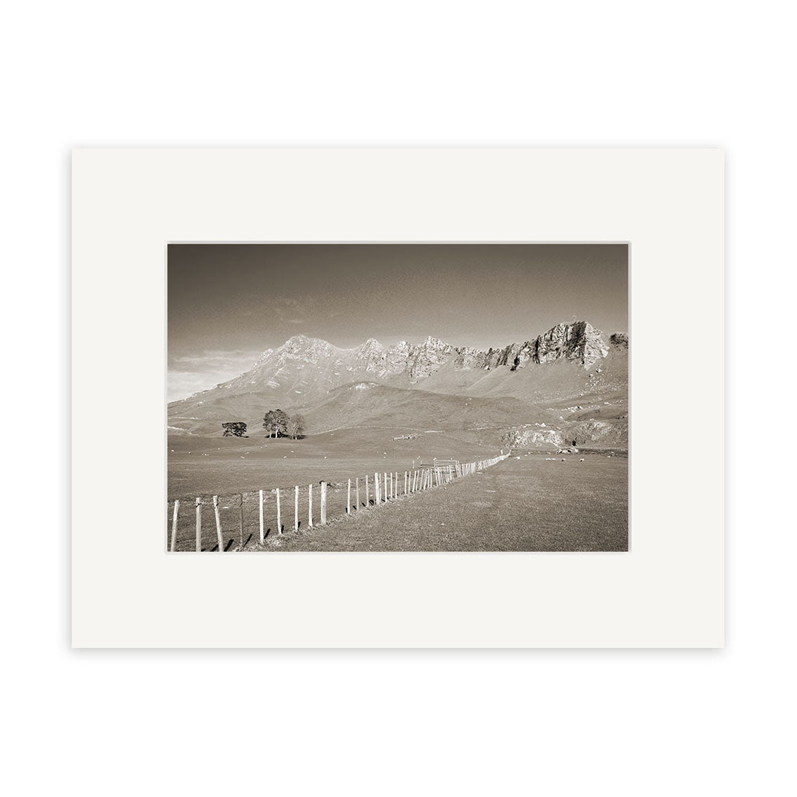 Black and white photograph titled Te Mata Peak - RP132 of a rural New Zealand landscape with a fence along a grassy field toward distant mountains, under a clear sky, framed by a white matte border on archival-quality matte paper.
