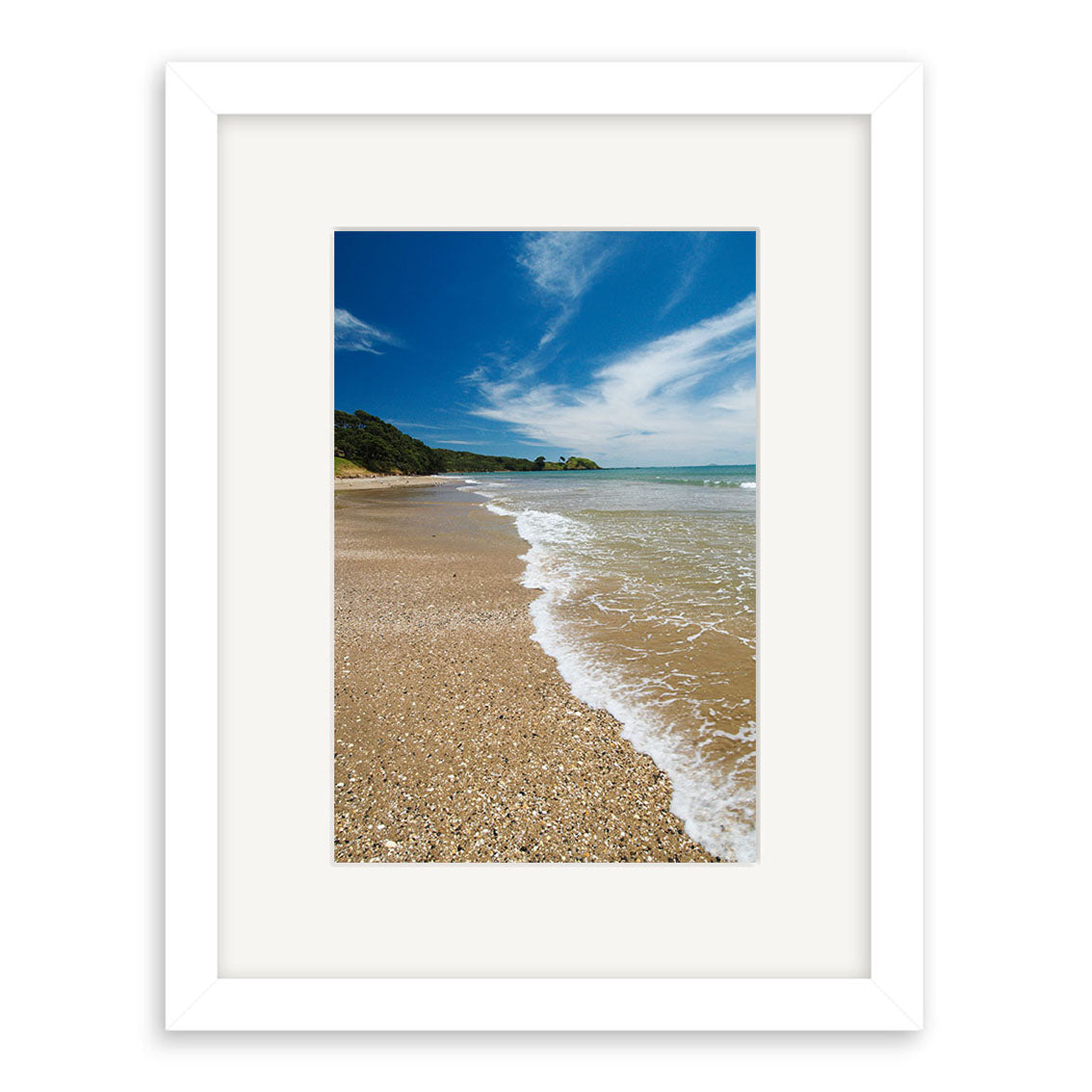Coopers Beach - RP138 is a framed photographic print by Reuben Price, featuring a sandy New Zealand beach, gentle waves, greenery, and a partly cloudy sky. The plain white frame with mat highlights this beautiful coastal scene.