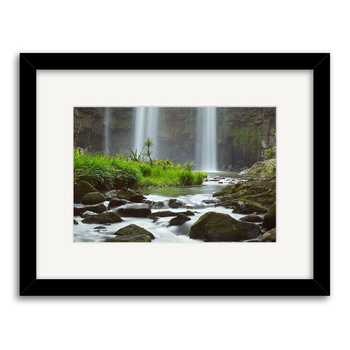 Whangarei Falls - RP139: An archival-quality framed photographic print of a tranquil waterfall cascading into a rocky stream among lush greenery, with a white mat and black frame for lasting beauty.