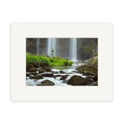 Whangarei Falls - RP139: A photograph of a New Zealand waterfall with rocks, moss, and green grass along a flowing stream—available as archival quality prints with wide white mat.