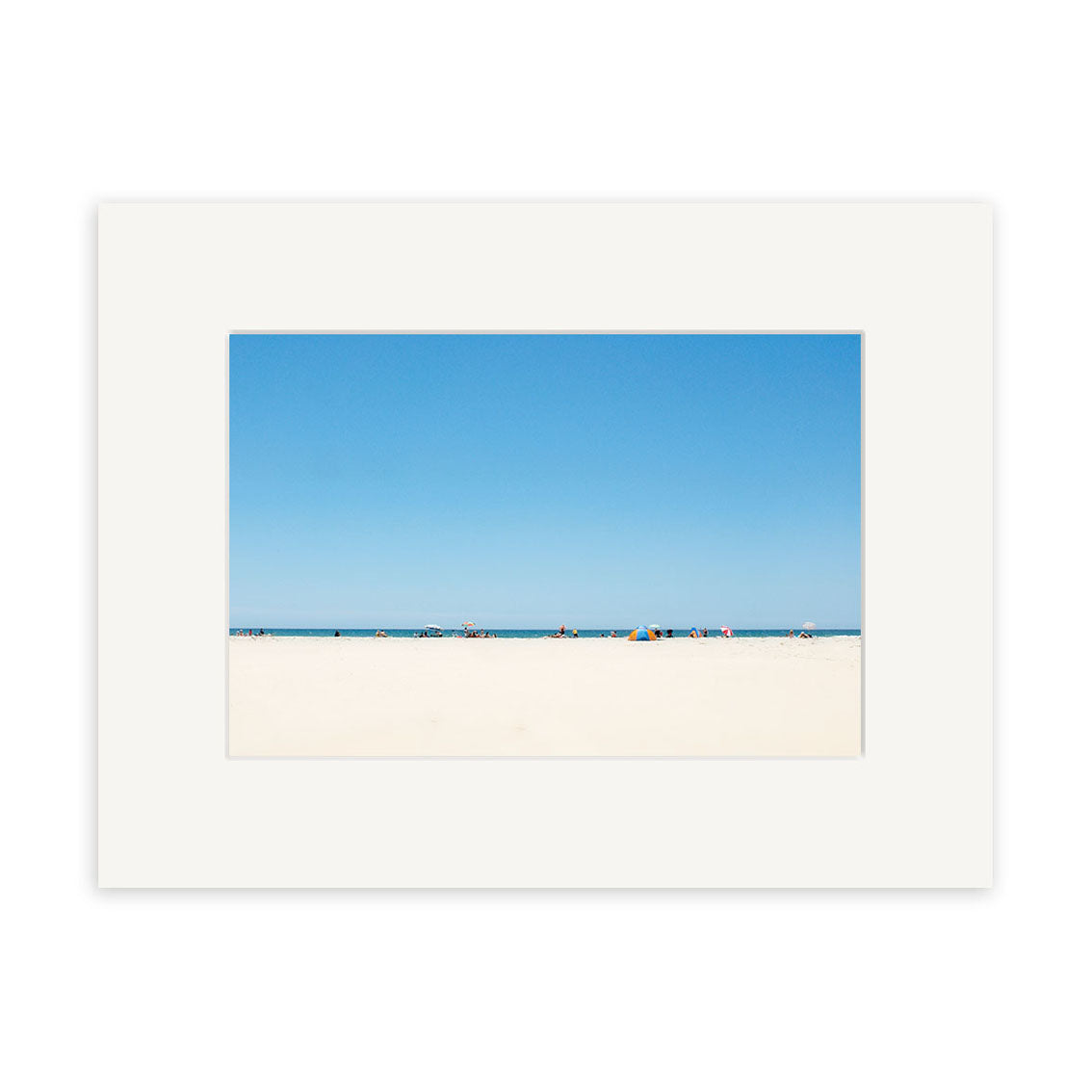 The Pakiri Beach - RP142 framed photographic print by Reuben Price showcases a sweeping view of white sand, distant figures, umbrellas, and clear blue sky—bringing the serene beauty of New Zealand’s coastline to your home.