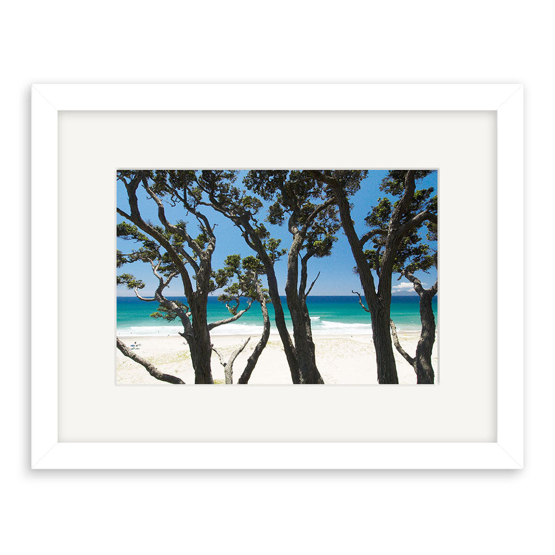 The Pakiri Beach - RP143 framed photographic print features dark tree trunks and branches against white sand and turquoise waves, set under a clear blue New Zealand sky. Printed on archival quality matte paper.