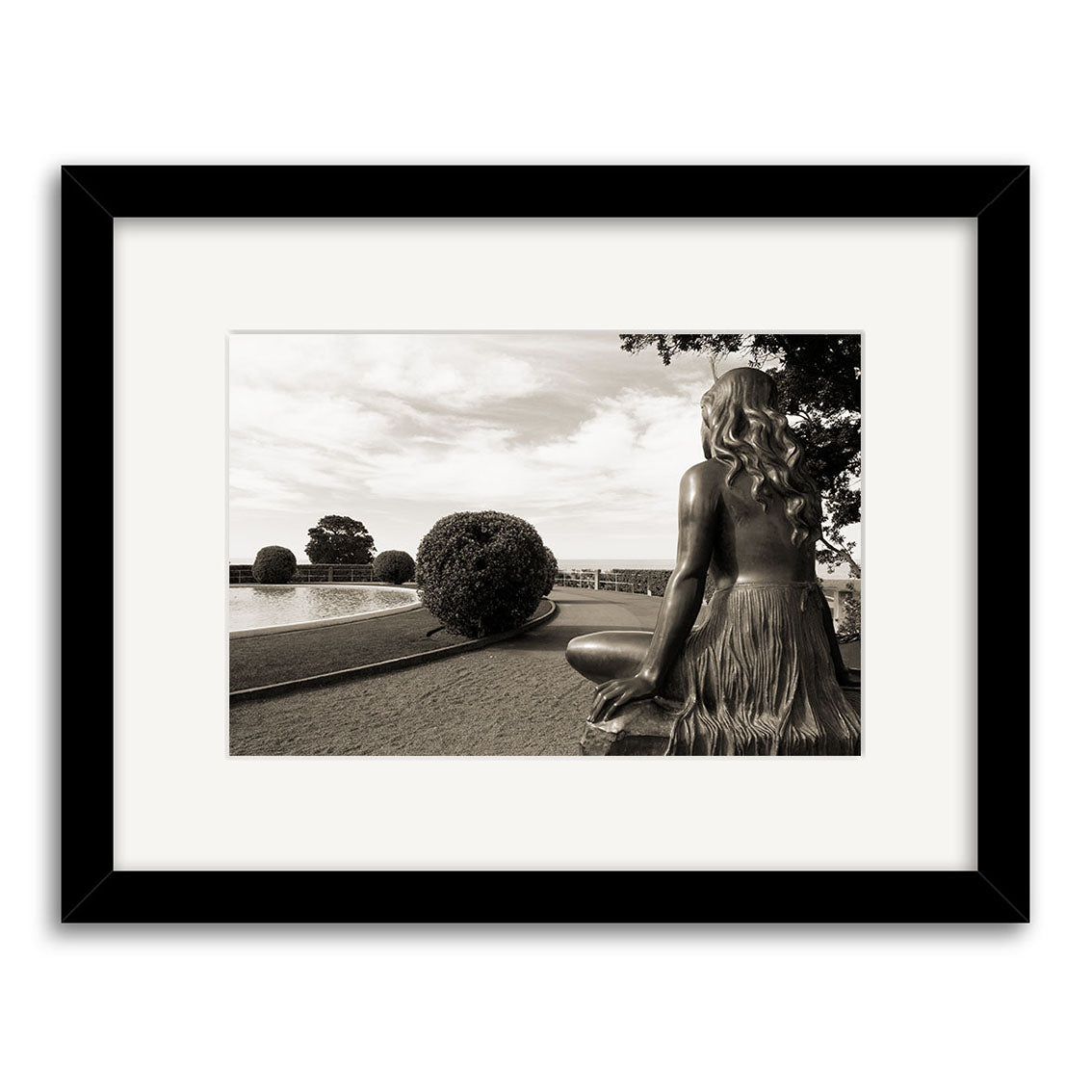 Pania of the Reef - RP144 features a black-and-white photo of a seated female statue in a New Zealand garden. Archival quality prints capture every detail, elegantly framed with a white mat and black frame.