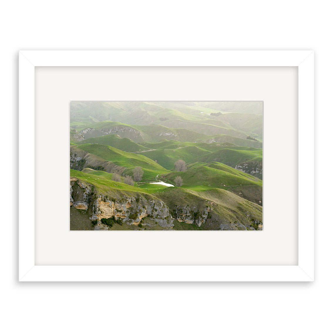 View from Te Mata - RP166: A framed photograph of New Zealand’s green hills, rocky outcrops, and a central pond. Displayed on white background and printed on archival quality matte paper for lasting beauty.
