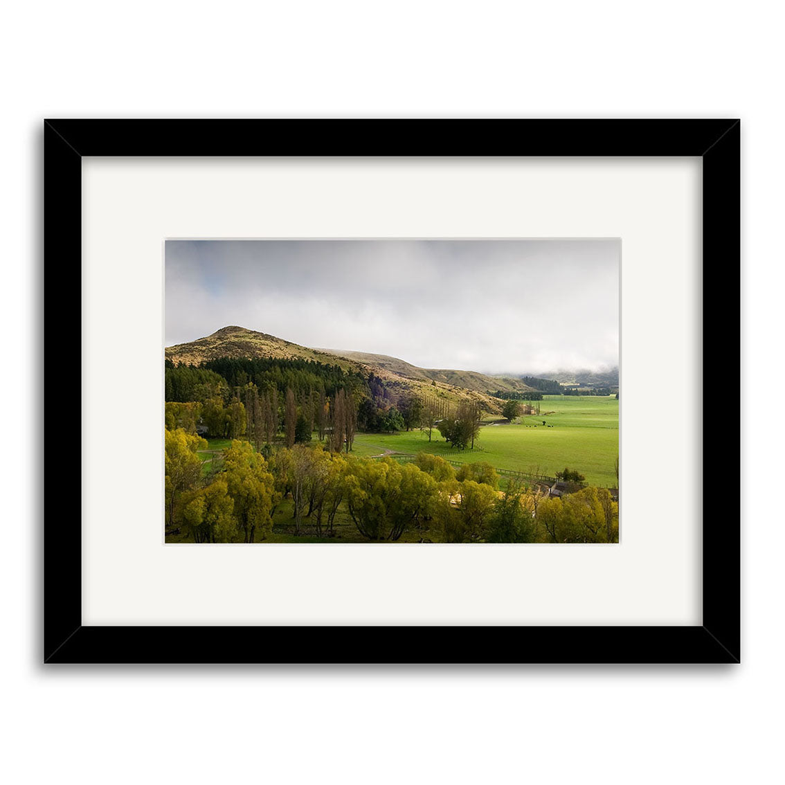 Framed photograph titled Inverary Station - RP176, showcasing a green rural landscape with rolling hills and cloudy skies, printed on archival matte paper and presented in a white mat with a sleek black frame.