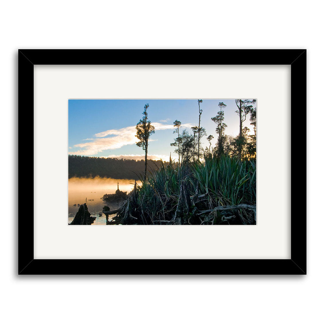 Framed photographic print Lake Wahapo - RP182 captures a sunrise lakeside scene in New Zealand, with tall grasses, misty water, and distant trees under a partly cloudy sky on archival quality matte paper.