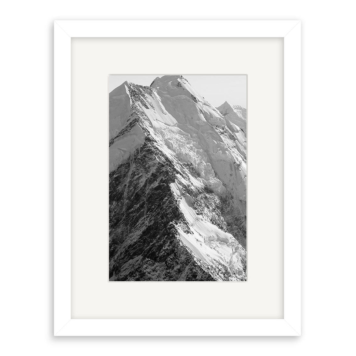 Mt Cook - RP185: Black and white photo of a snow-covered peak by Reuben Price, in a white mat and frame. Printed on archival matte paper, it showcases the striking beauty of New Zealand.