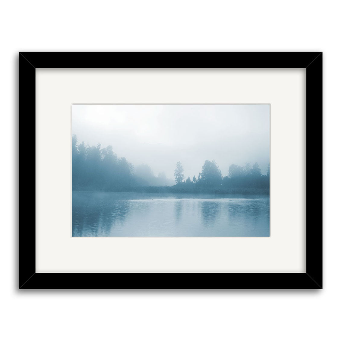 The Misty Lake Matheson – RP186 by Reuben Price is a New Zealand photographic print featuring a tranquil lake and misty trees in blue tones, printed on archival matte paper and presented in a black frame with white mat.
