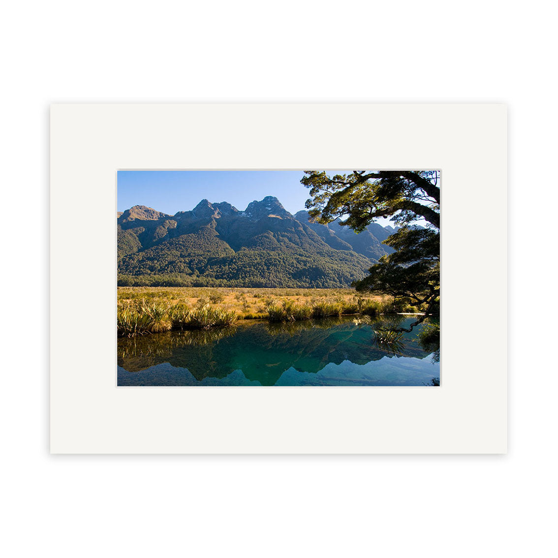 Mirror Lakes - RP190 by Reuben Price is a matted photographic print featuring mountains, forest, grassy field, and their reflection in calm blue water.