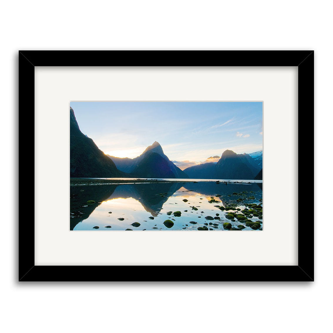Milford Sound - RP191: A Reuben Price photographic print of a mountain landscape at sunrise or sunset, with calm water reflections. Printed on archival quality matte paper, presented in a black frame with white matting.