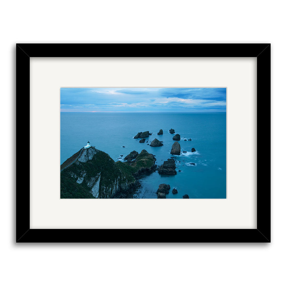 Experience New Zealand’s stunning coast with Nugget Point Caitlins - RP214, a framed photographic print featuring rocky islets, a winding path to a lighthouse, and vibrant skies on archival quality matte paper.