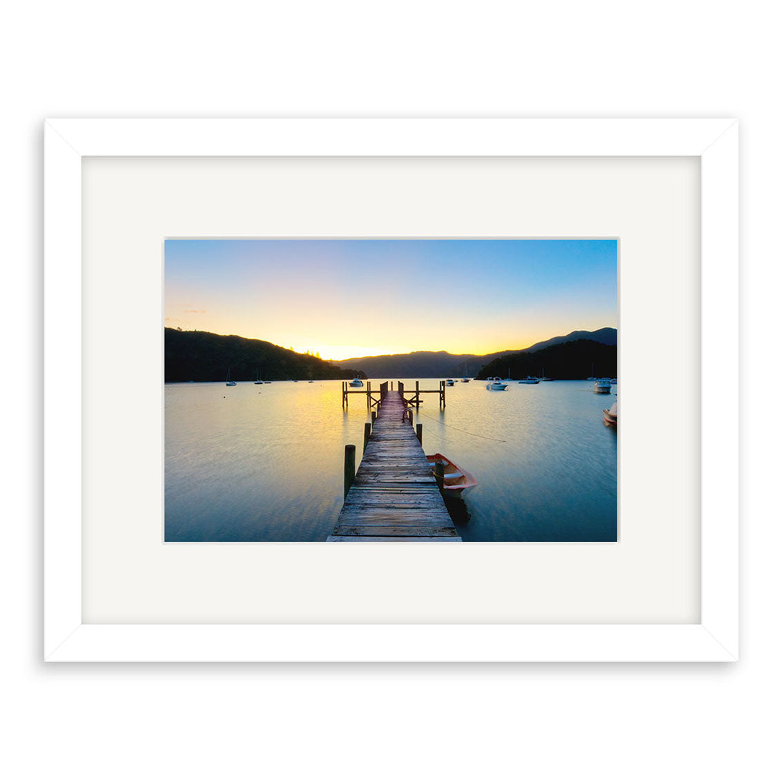 The Marlborough Sounds - RP220 is a framed photographic print of a wooden pier at sunset, stretching into a calm New Zealand lake with hills and boats, printed on archival-quality matte paper for enduring beauty.