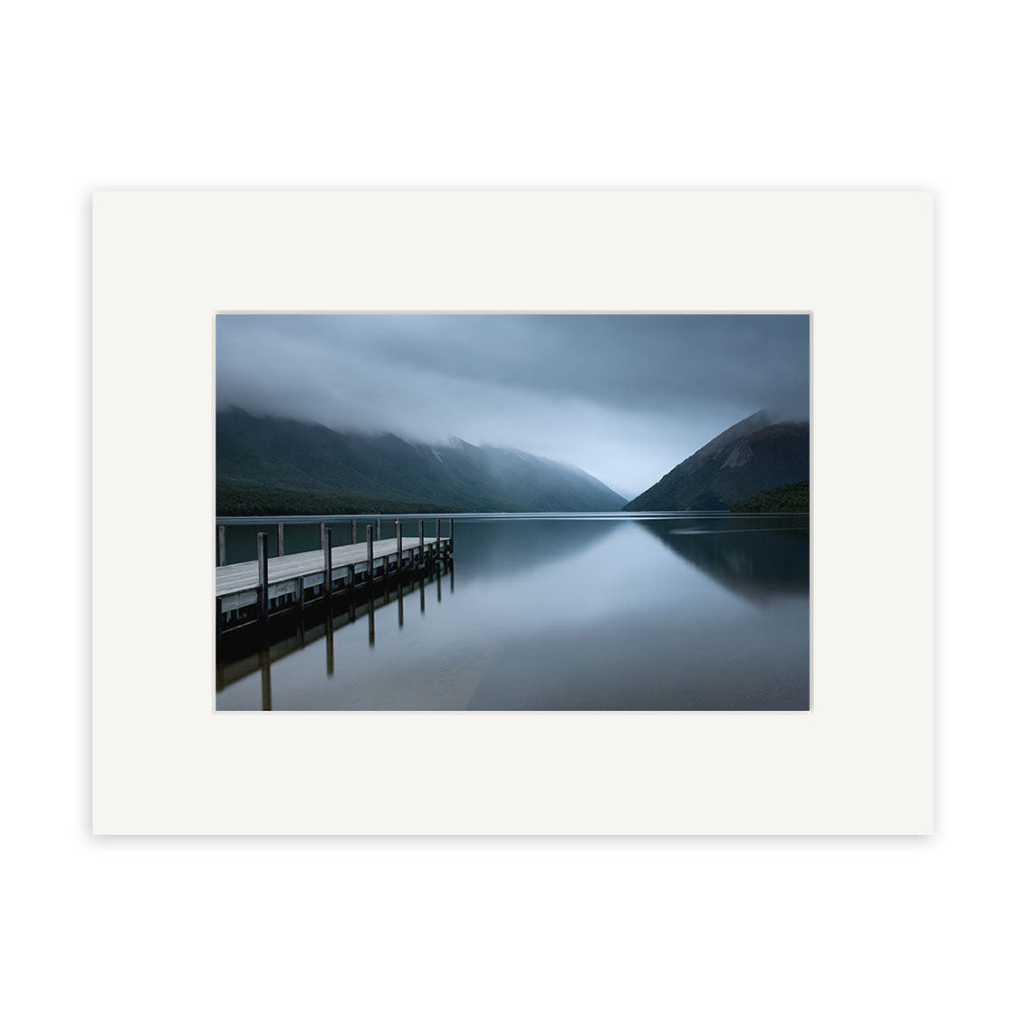 The tranquil scene Lake Rotoiti - RP221 shows a wooden dock stretching into a reflective lake with misty New Zealand mountains under clouds, all in blue-grey tones—ideal for photographic prints on archival quality matte paper.