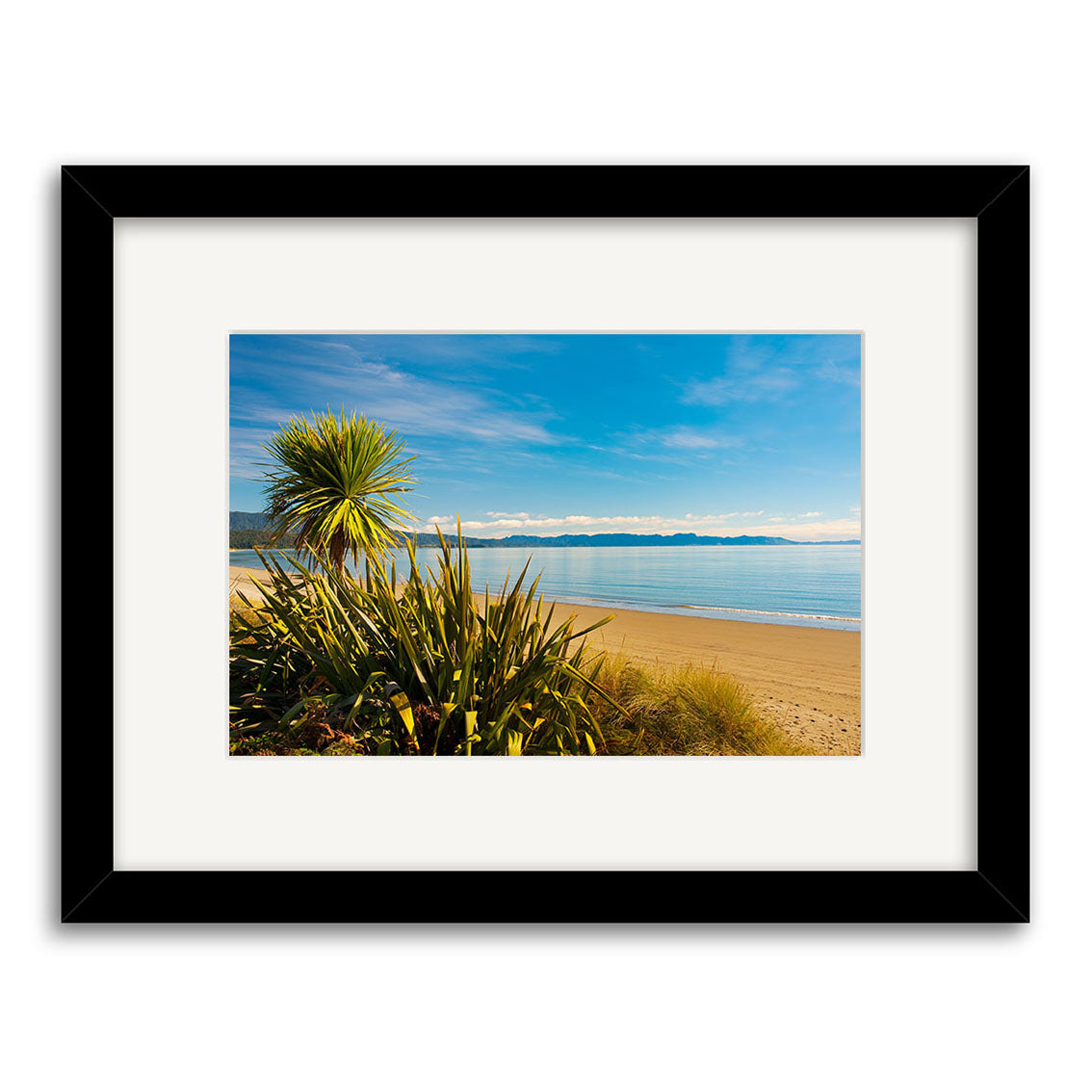 Golden Bay - RP222: Framed photographic print of a sandy New Zealand beach with blue sky, calm sea, and green plants. Image is centered in a white mat and black frame, printed on archival-quality matte paper.