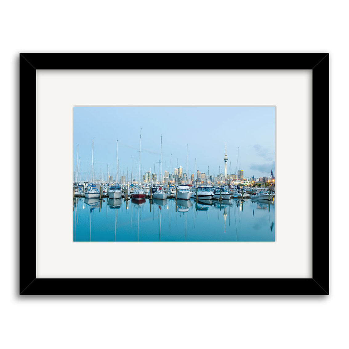 The Westhaven - RP230 is a framed photographic print of a New Zealand marina with sailboats, calm waters, city buildings, and a tall tower under a clear blue sky on archival quality matte paper.