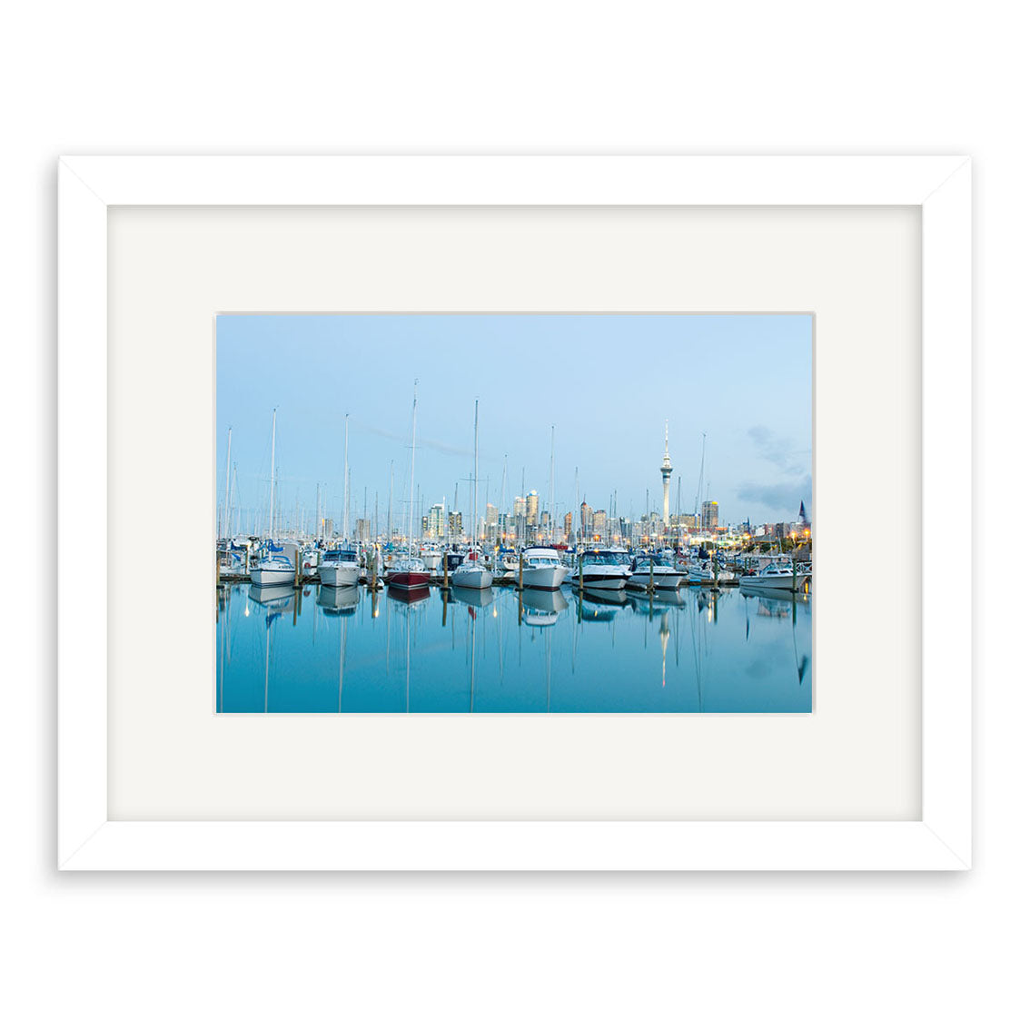 The Westhaven - RP230 is a framed photographic print featuring a marina with docked sailboats, calm water reflecting the city skyline, and a clear blue sky, beautifully presented on archival quality matte paper.
