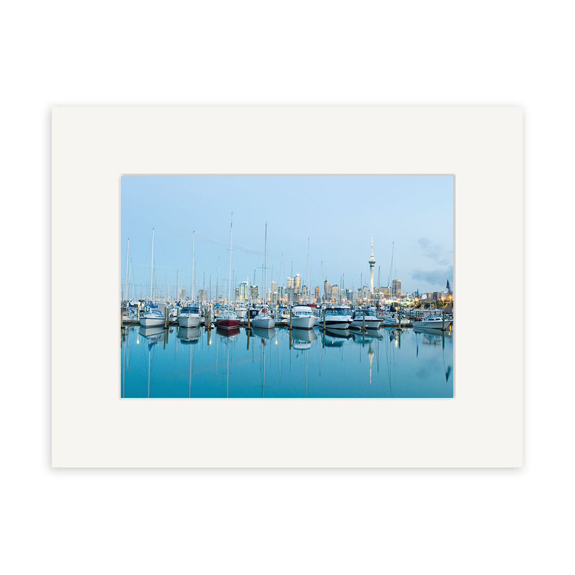 Westhaven - RP230 features a marina with sailboats on calm water, city buildings and a tall tower in the background under a clear blue sky. Printed on archival matte paper with a white matte frame for lasting beauty.
