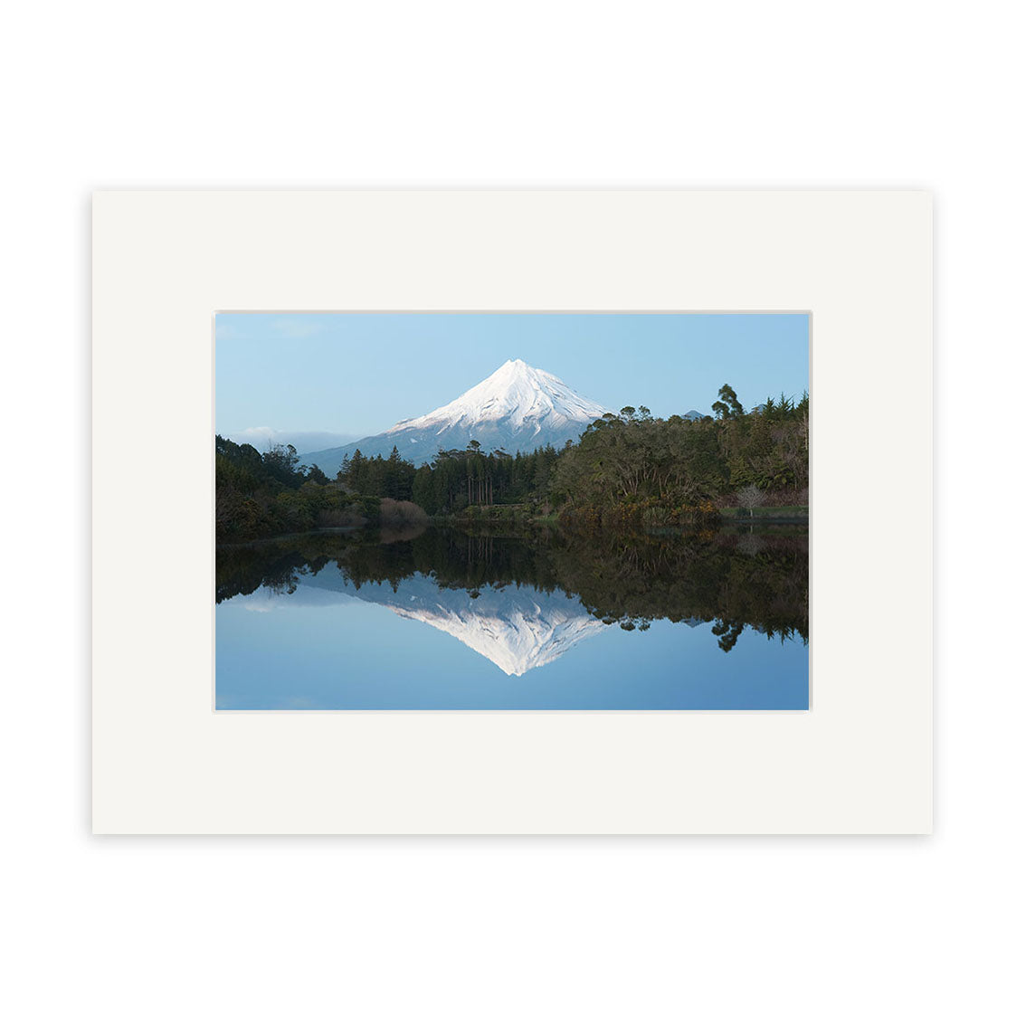 Lake Mangamahoe - RP239 features a snow-capped New Zealand mountain reflected in a tranquil lake, framed by trees and a clear blue sky. Displayed with a white mat frame, its ideal for showcasing archival quality photographic prints.
