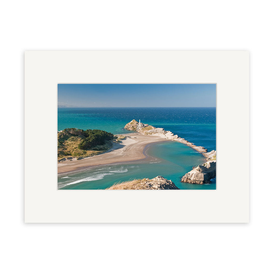 Aerial view of Castlepoint - RP246: a sandy peninsula in New Zealand with winding shoreline, clear blue water, green vegetation, and a white lighthouse—bordered by a white mat frame for archival quality matte paper prints.