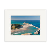 Aerial view of Castlepoint - RP246: a sandy peninsula in New Zealand with winding shoreline, clear blue water, green vegetation, and a white lighthouse—bordered by a white mat frame for archival quality matte paper prints.