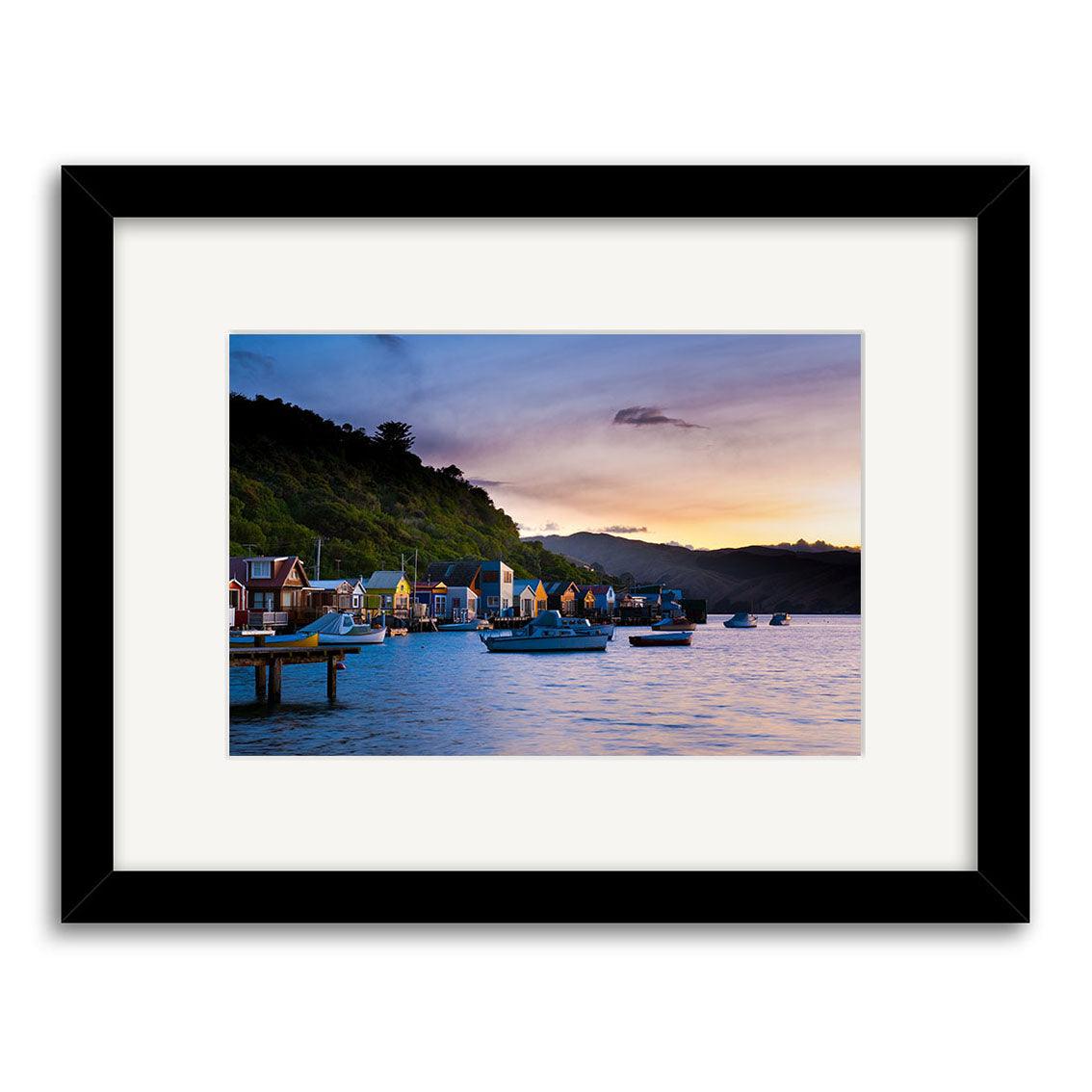 Framed photographic print Paremata - RP248 captures a New Zealand harbor at sunset, with boats, colorful houses on green hills, and a partly cloudy sky, beautifully printed on archival-quality paper.