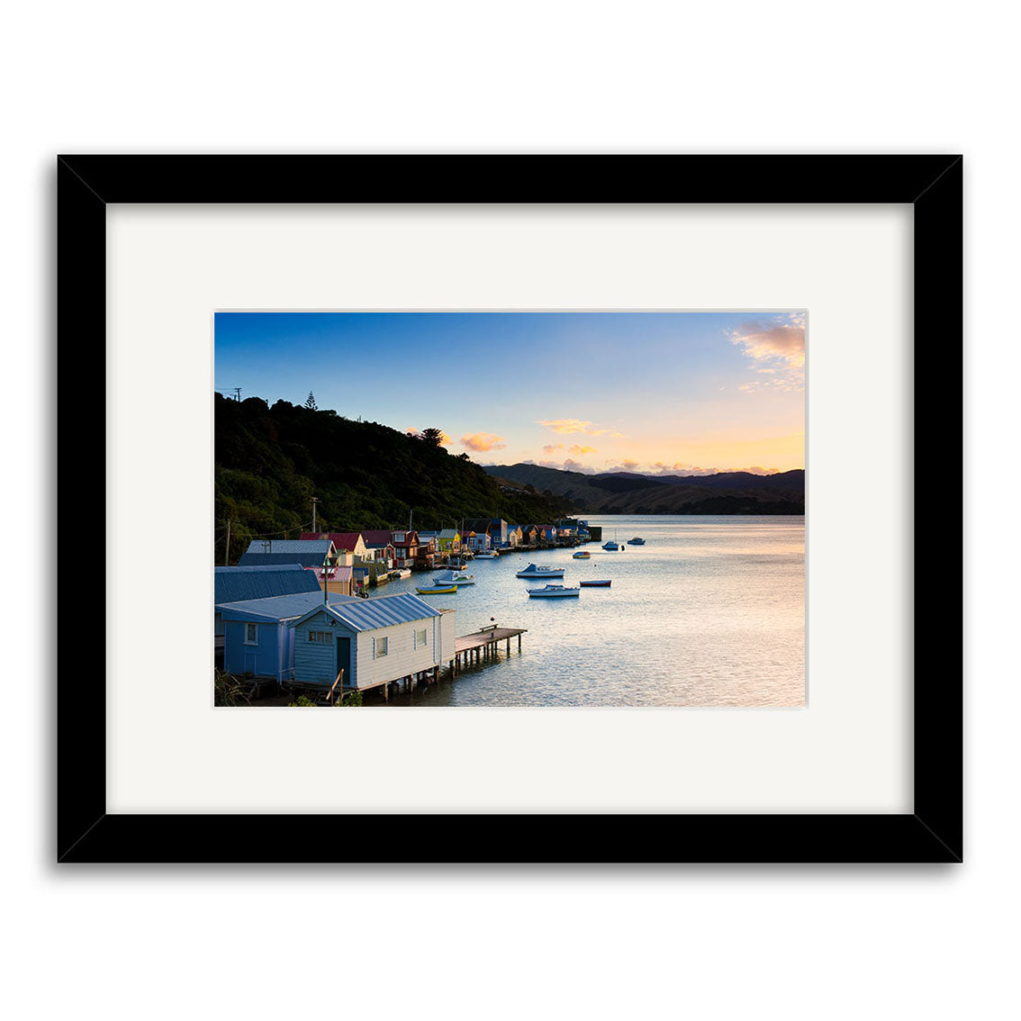 Paremata View - RP249: Framed photo by renowned NZ photographer Reuben Price. Features boat sheds, calm waters, and distant hills at sunset. Archival quality prints available.