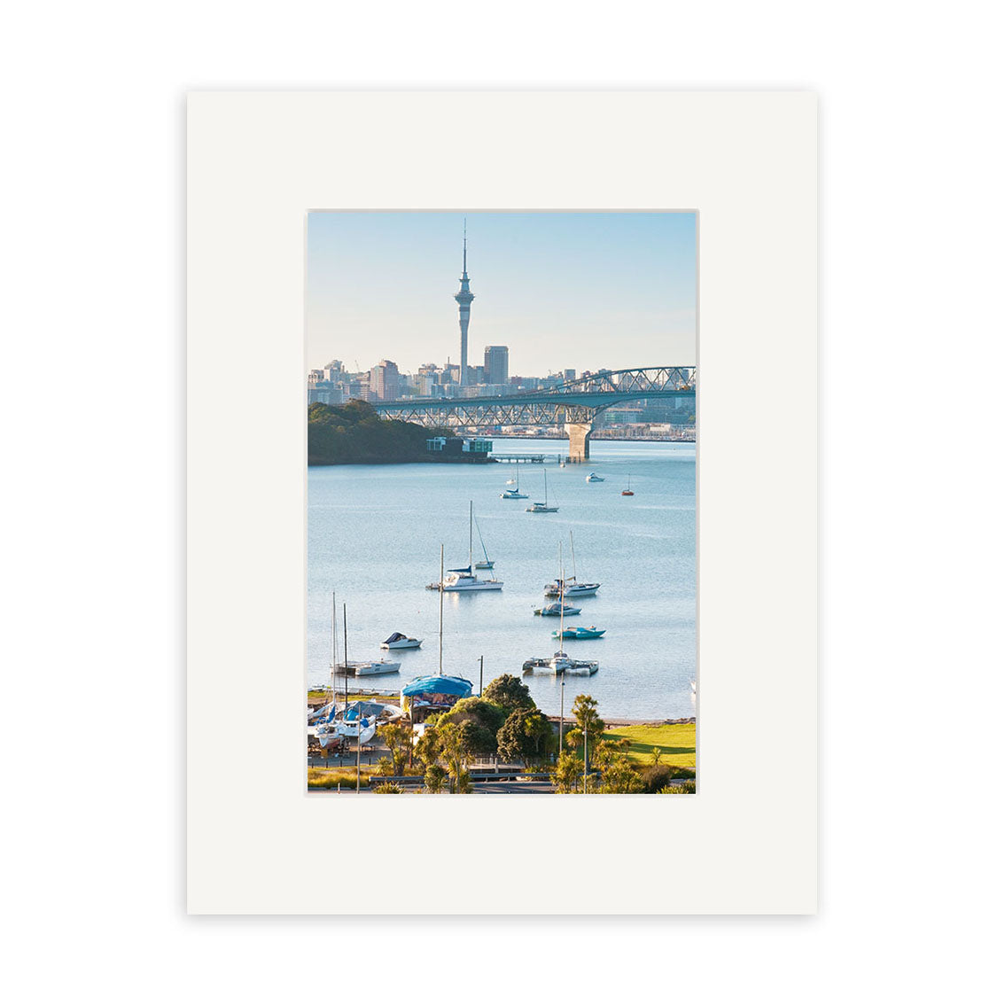 A photo titled Little Shoal Bay - RP252 shows a calm harbor with anchored sailboats, a bridge, and a city skyline with a tall tower, all framed by a white mat border. Available as archival quality photographic prints.