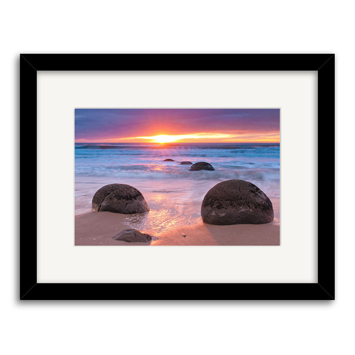 Framed archival-quality photographic print titled Moeraki Boulders - RP262 featuring large round boulders on a New Zealand beach at sunset, with waves and a colorful sky in the background.
