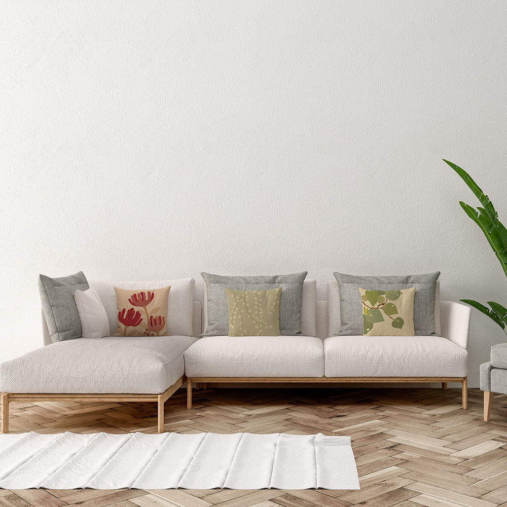 A modern living room with a white sectional sofa adorned with four Raw Kowhai Linen Cushion Covers, a light wood herringbone floor, a large green plant on the right, and a white rug in front of the sofa.