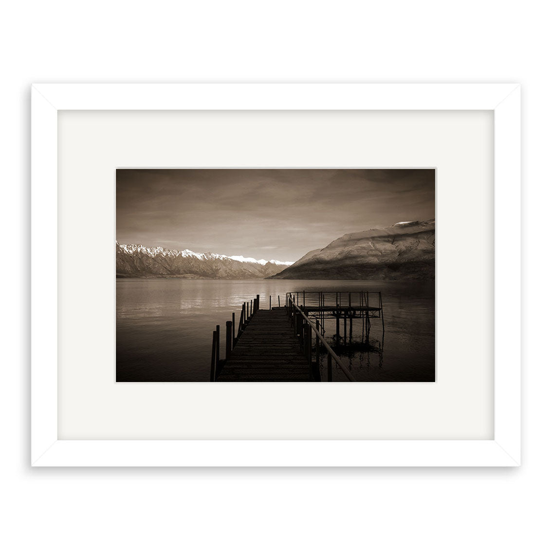Lake Wakatipu Wharf - RP066: A framed, sepia photograph of a wooden pier stretching into a tranquil New Zealand lake with mountain views beneath cloudy skies, printed on archival matte paper for lasting quality.