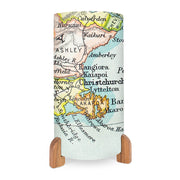 The Vintage Canterbury Map Table Lamp features a cylindrical design with wooden legs and displays a vibrant printed map of New Zealand’s Canterbury region, highlighting cities like Christchurch, Akaroa, Rangiora, and nearby areas.