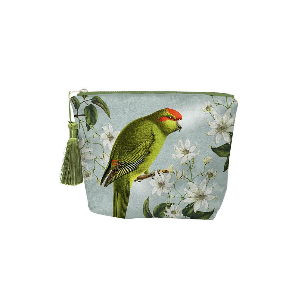 The Birds & Botanicals Kakariki Velvet Cosmetic Bag features a green and red parrot inspired by New Zealand birds, illustrated among white flowers and green leaves on light blue velvet, with a stylish green tassel on the zipper.