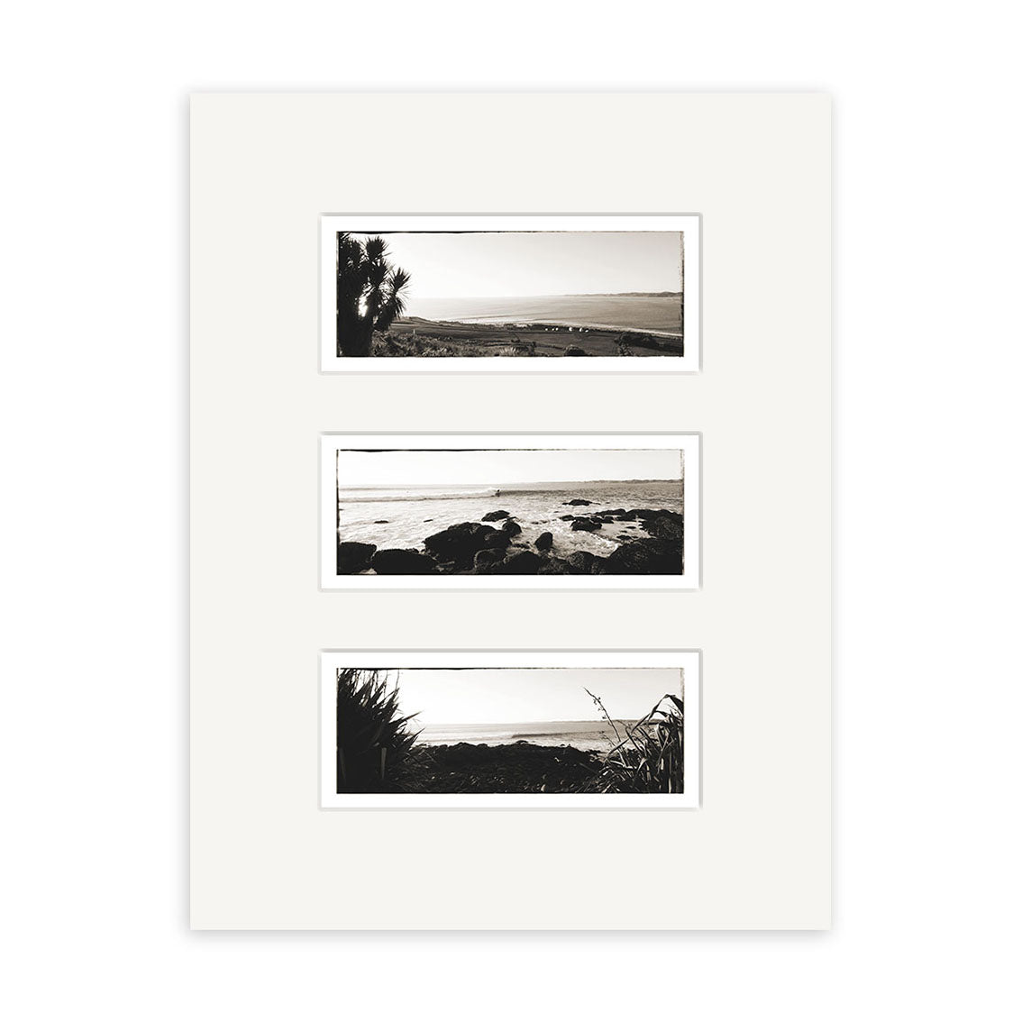The Raglan Triptych - RP096 features three vertically arranged black-and-white photos of New Zealand’s rocky coastline with vegetation, printed on archival quality matte paper in a white mat.