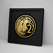 The 2 Cent Coin Foil Print features gold foil art of two birds on leafy branches beside the number 2, in a black frame that leans against a white wall for a modern Kiwiana touch.