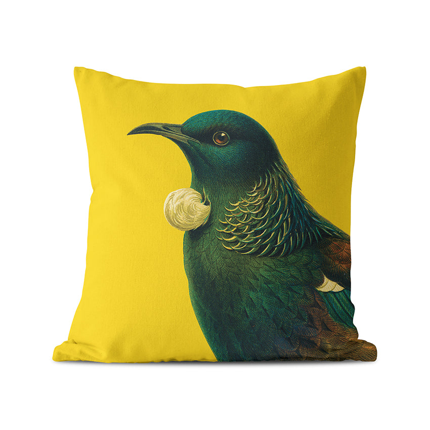The Bright Tui Cushion Cover is a square, yellow polyester cover from the Bright Birds Range, featuring a realistic tui bird with iridescent feathers and white throat tufts, designed in New Zealand.