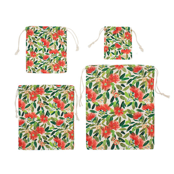 The Pohutukawa Print Drawstring Bag Set features four reusable cotton bags in various sizes, each with a vibrant red and green pohutukawa flower print on white, arranged in a grid.