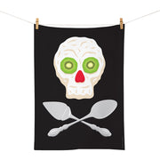 The Glenn Jones - Pavlova Pirate Tea Towel is a black cotton towel designed in New Zealand, featuring a skull made from pavlova with kiwi eyes and a red nose above crossed spoons, inspired by NZ artist Glenn Jones.