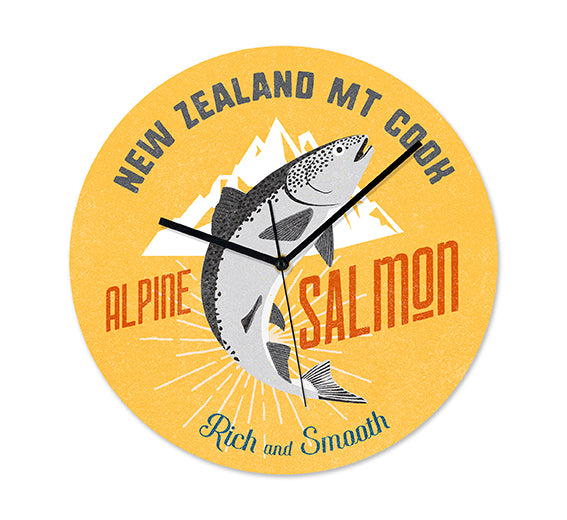 The NZ Seafood Salmon Frameless Clock is round and yellow, showing a leaping salmon before white mountains with New Zealand Mt Cook, Alpine Salmon, Rich and Smooth text. Black silent hands complete this New Zealand-inspired design.