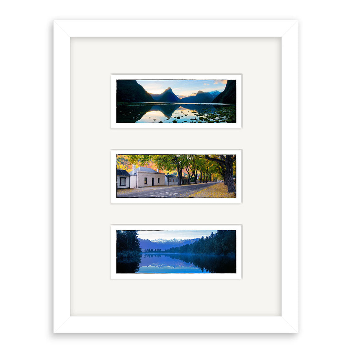 The South Island Triptych 1 - RP195 is a white-framed collage with three horizontal landscape prints: a lake with mountains, an autumn tree-lined building, and a lake with trees and snow-capped peaks by Reuben Price.