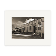 A sepia photo features the historic Cardrona Pub - RP071 in New Zealand, with a vintage car, wooden façade, hotel and garage signs, and rocky landscaping captured in stunning detail for photographic prints.