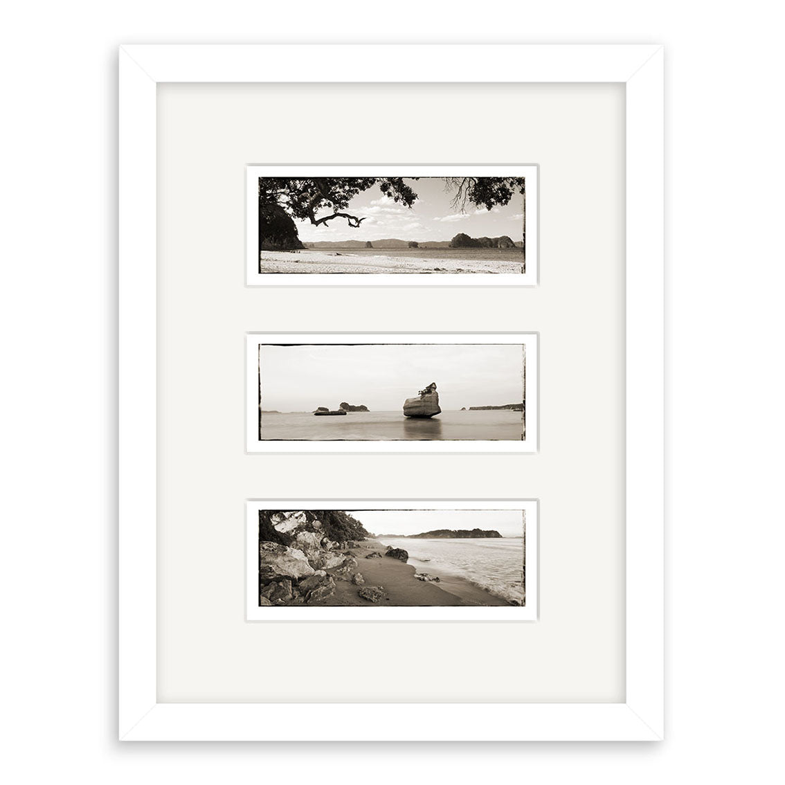 Coromandel Triptych - RP124: A white-framed set of three archival quality matte prints, each separated by wide white matting, featuring black-and-white views of a rocky New Zealand shoreline and ocean arranged vertically.